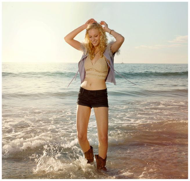 Junge blonde Frau mit Westernstiefel im Meer