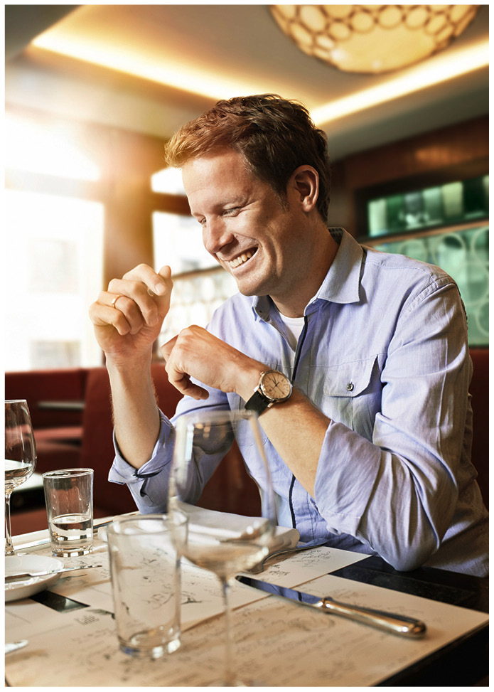 Lachender Mann mit aufgestützten Ellbogen in einem Restaurant