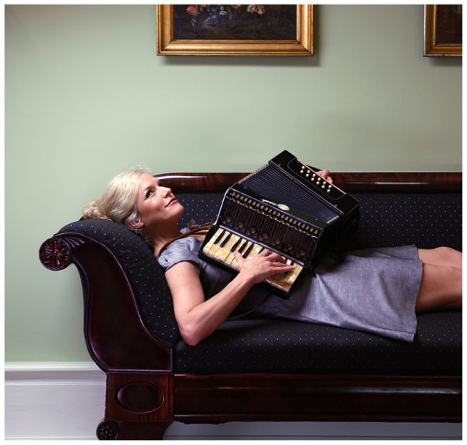 Saengerin und Moderatorin Ina Mueller liegt mit einem Akkordeon auf einem Sofa