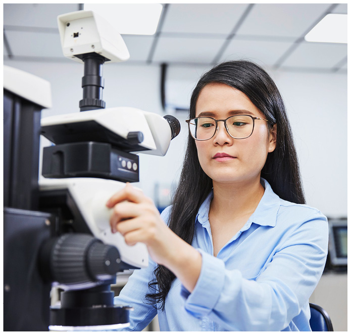 Chinesische Frau arbeitet bei Osram an einem Mikroskop