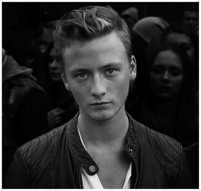 Portrait von Phillip vor einer Menschengruppe schwarz weiss