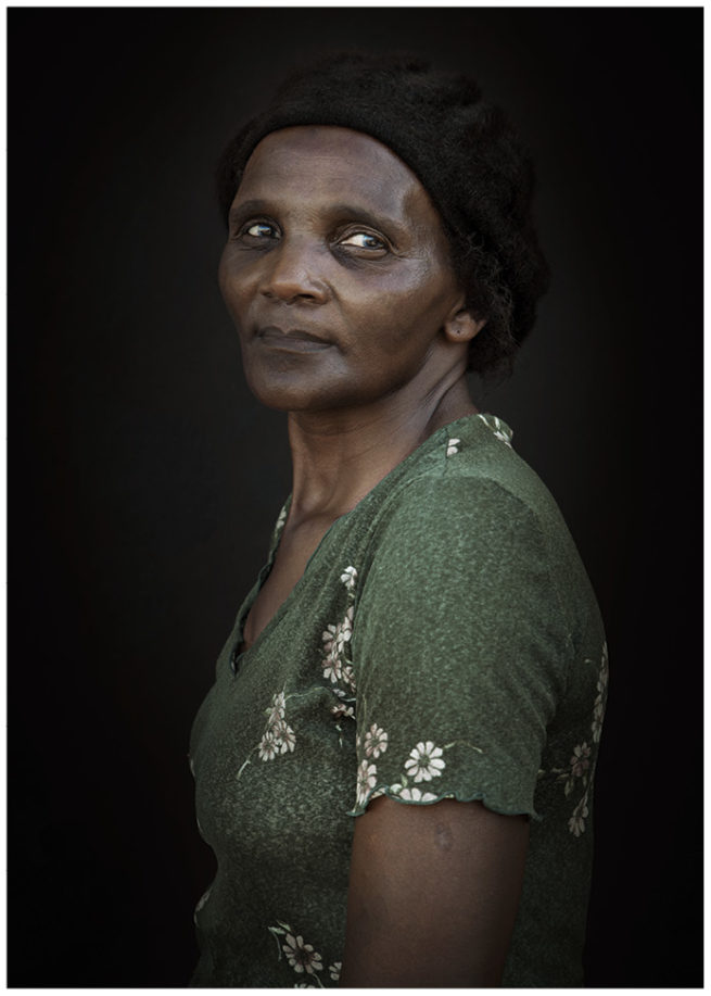 Portrait einer stolzen schwarzen Südafrikanerin mit schwarzer Mütze vor schwarzem Hintergrund