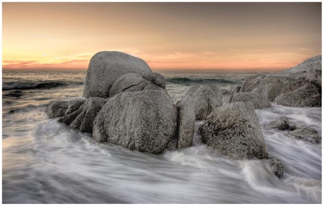 Aberundete Felsen im Sonnenuntergang in Kapstadt die von Wasser umspült werden