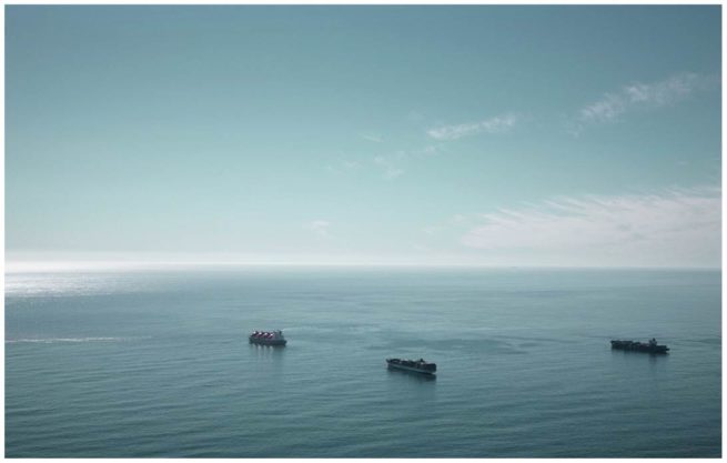 Luftaufnahme von einem weiten Meer mit drei Containerschiffen