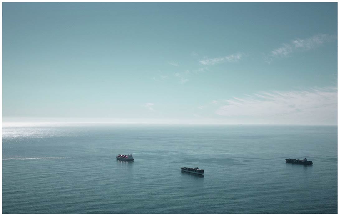 Luftaufnahme von einem weiten Meer mit drei Containerschiffen