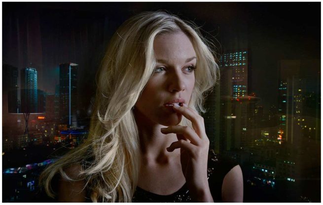 Portrait einer blonden jungen Frau vor einer nächtlichen Skyline