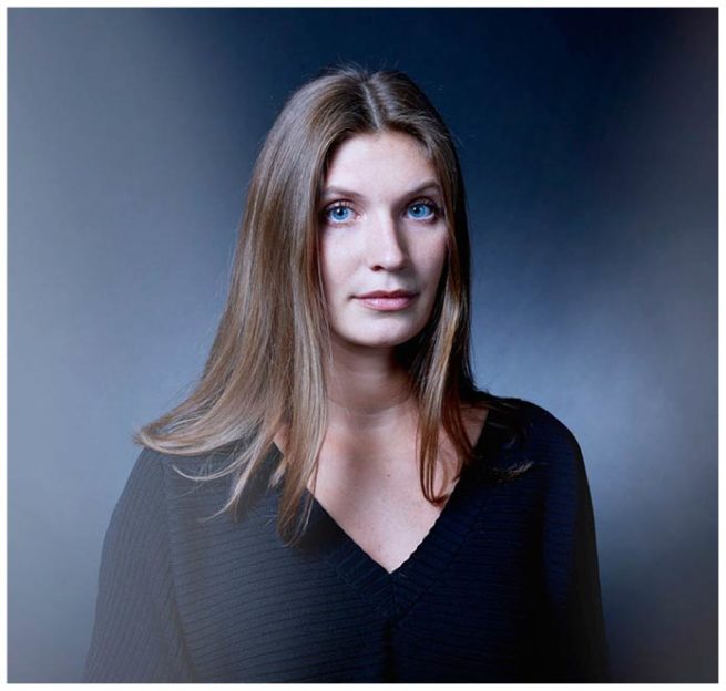 Portrait einer jungen Frau mit leuchtenden blauen Augen vor einem blauen Hintergrund